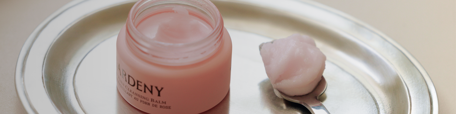 Gardeny Rose PDRN Cleansing Balm displayed on a silver tray beside a smooth scoop of its sherbet-like texture, highlighting the Korean plant-based PDRN blend that melts makeup without stripping hydration. Soft, radiant lighting reinforces Gardeny’s gentle, moisture-restoring cleansing ritual ideal for first-time PDRN users.