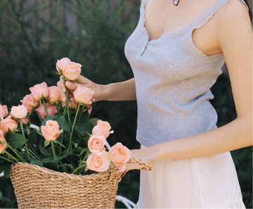 Woman outdoors holding a woven basket filled with freshly cut pink roses, evoking Gardeny’s botanical inspiration and the natural origins of its Rose PDRN formulas. The serene scene reflects the Reset & Refresh Mini Duo’s gentle, rose-centered cleansing ritual rooted in hydration, purity, and daily skin renewal, aligned with Gardeny’s flower-powered Korean skincare identity.