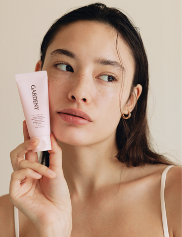 Model with fresh, dewy skin holding the Gardeny Rose PDRN Mask Cleanser beside her face, emphasizing its creamy mask-to-foam formula enriched with plant-based Damask Rose PDRN. The image conveys Gardeny’s gentle Korean cleansing approach focused on hydration, radiance, and skin comfort, ideal for users seeking non-stripping cleansers that support moisture retention.