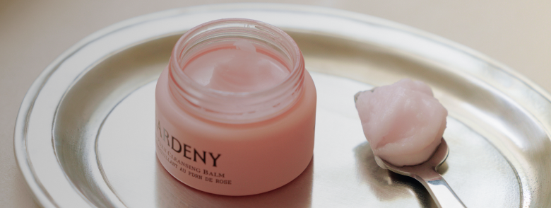 Gardeny Rose PDRN Cleansing Balm displayed on a silver tray beside a smooth scoop of its sherbet-like texture, highlighting the Korean plant-based PDRN blend that melts makeup without stripping hydration. Soft, radiant lighting reinforces Gardeny’s gentle, moisture-restoring cleansing ritual ideal for first-time PDRN users.