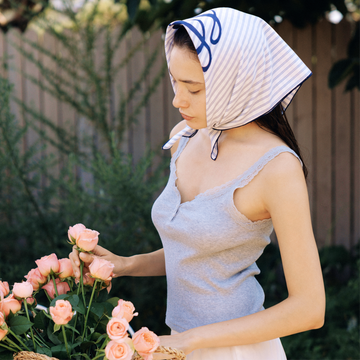 Woman outdoors holding a woven basket filled with freshly cut pink roses, evoking Gardeny’s botanical inspiration and the natural origins of its Rose PDRN formulas. The serene scene reflects the Reset & Refresh Mini Duo’s gentle, rose-centered cleansing ritual rooted in hydration, purity, and daily skin renewal, aligned with Gardeny’s flower-powered Korean skincare identity.