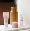 Gardeny Essential Mini Trio arranged beside a ceramic vase on a window ledge in natural light, featuring the mini mask cleanser, cleansing balm, and Rose PDRN mist toner. This setting highlights the trio’s calming, travel-ready design and its ability to restore balance, hydration, and radiance through gentle, rose-infused formulas suitable for everyday routines.