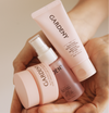 Hands holding the Gardeny Essential Mini Trio, mini cleansing balm, mist toner, and mask cleanser, emphasizing their compact size and soft pink design. The image conveys the convenience of a portable 3-step routine offering gentle cleansing, hydration, and Rose PDRN-powered skin repair, perfect for maintaining a refreshed glow anywhere.